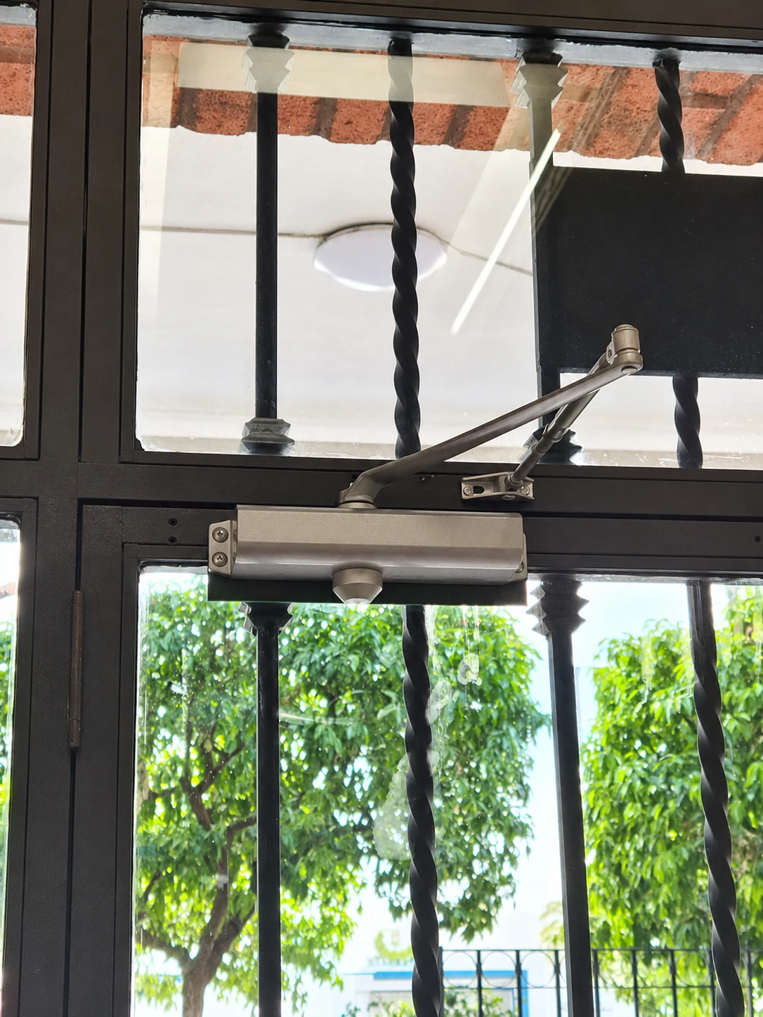 Cierrapuertas hidráulico instalado en una puerta de comunidad